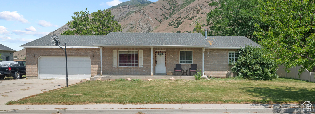 Ranch-style house featuring covered porch, concrete driveway, an attached garage, a front lawn, and brick siding