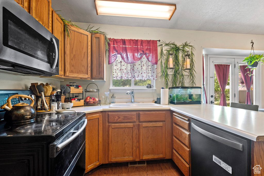 Kitchen with appliances with stainless steel finishes, a sink, a peninsula, and light countertops