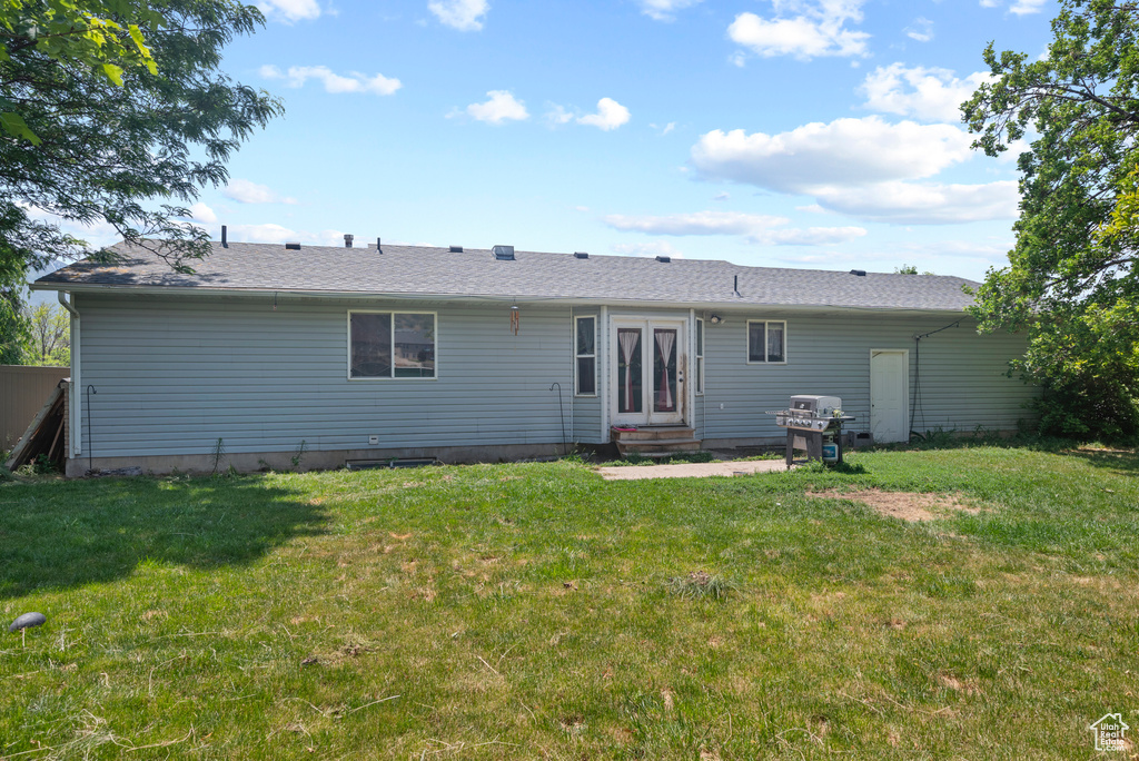 Back of house with entry steps and a lawn