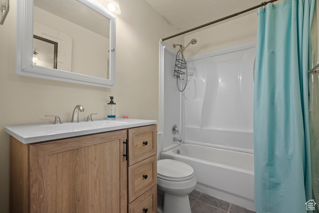 Bathroom with shower / bathtub combination with curtain, toilet, vanity, and tile patterned floors