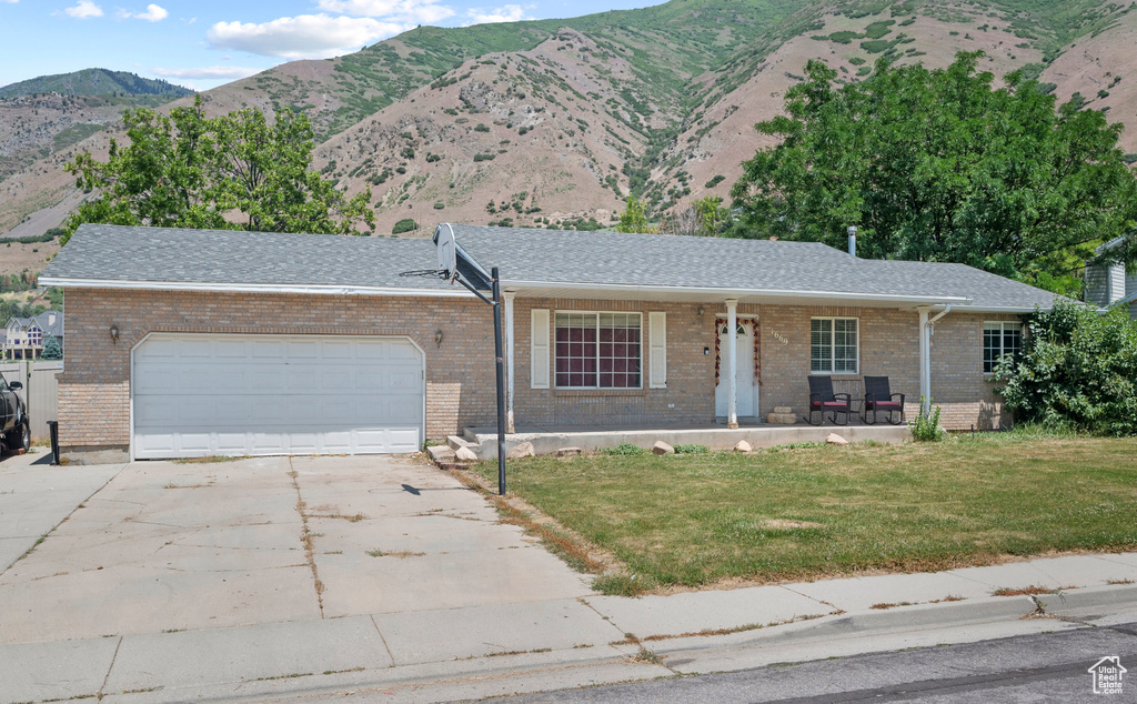 Ranch-style house with a porch, a front lawn, a garage, driveway, and brick siding