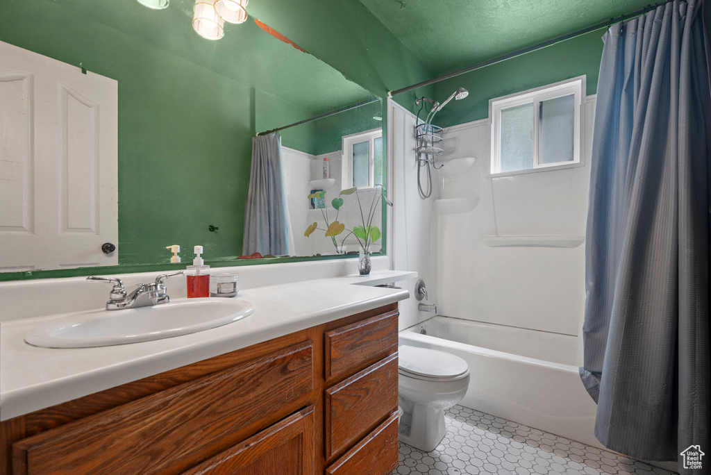 Bathroom featuring toilet, vanity, shower / bathtub combination with curtain, and a textured ceiling