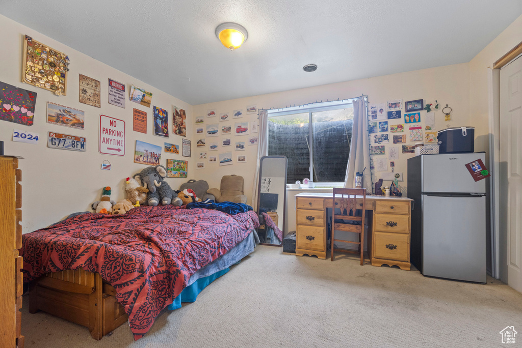Bedroom with freestanding refrigerator and carpet flooring