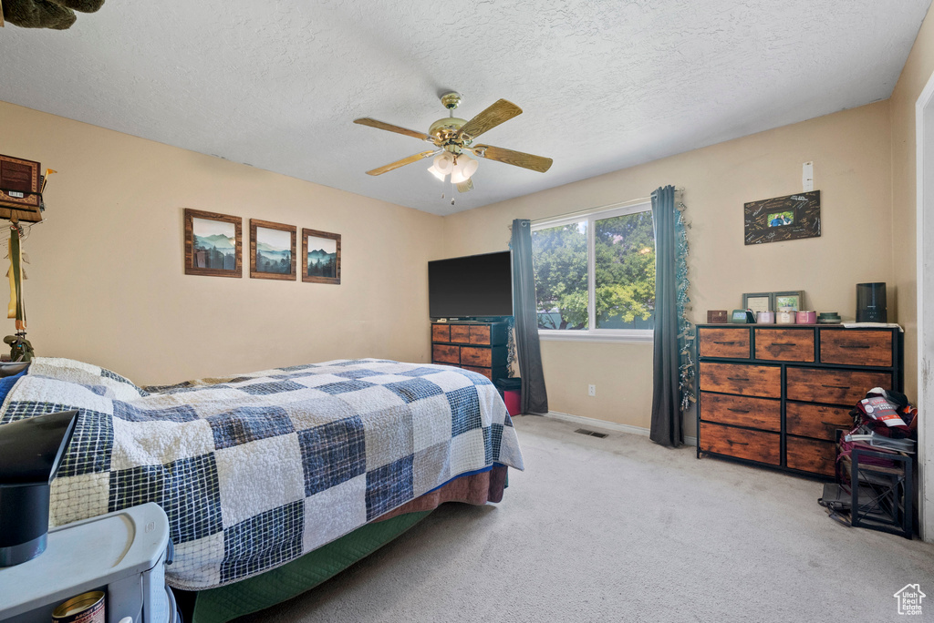 Bedroom featuring carpet floors, a textured ceiling, baseboards, and ceiling fan