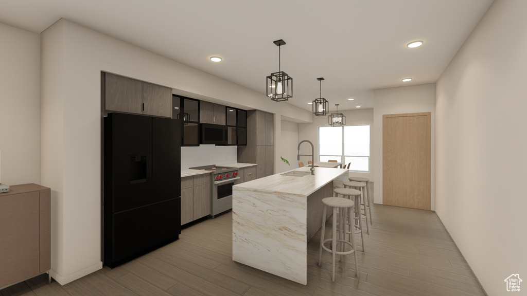 Kitchen with black fridge, stainless steel stove, a sink, a kitchen bar, and light countertops