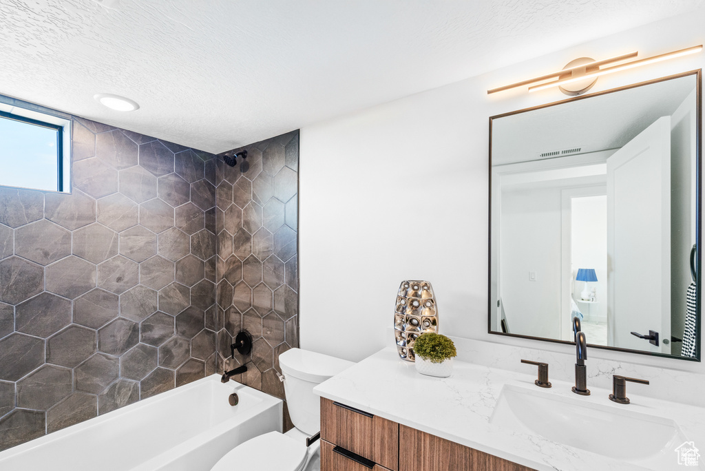 Bathroom with vanity, toilet, shower / tub combination, and a textured ceiling
