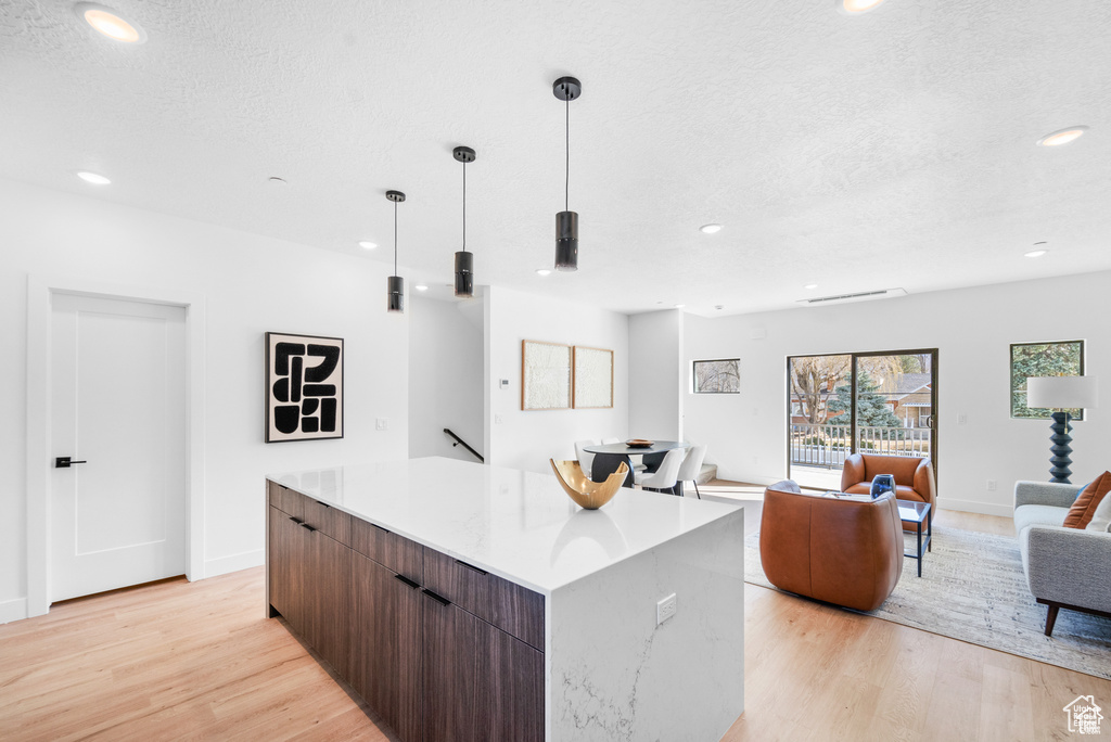 Kitchen with a kitchen island, light wood-style floors, modern cabinets, recessed lighting, and a textured ceiling