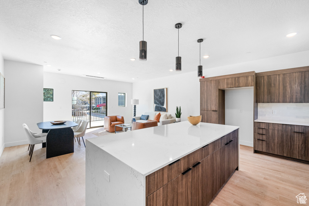 Kitchen featuring modern cabinets, light wood-style floors, light countertops, a kitchen island, and recessed lighting