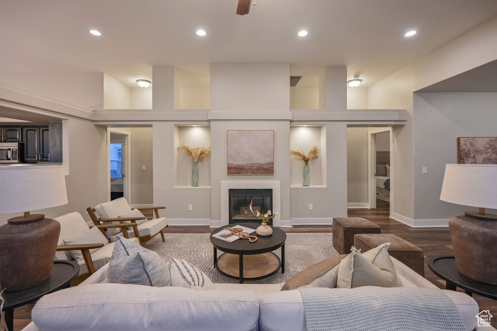 Living room featuring dark wood-style floors, recessed lighting, a glass covered fireplace, baseboards, and ceiling fan
