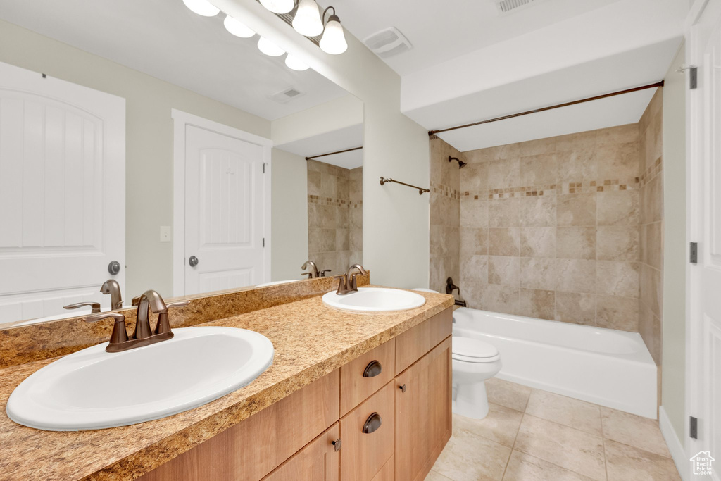 Full bath featuring double vanity, toilet, tile patterned flooring, and bathing tub / shower combination