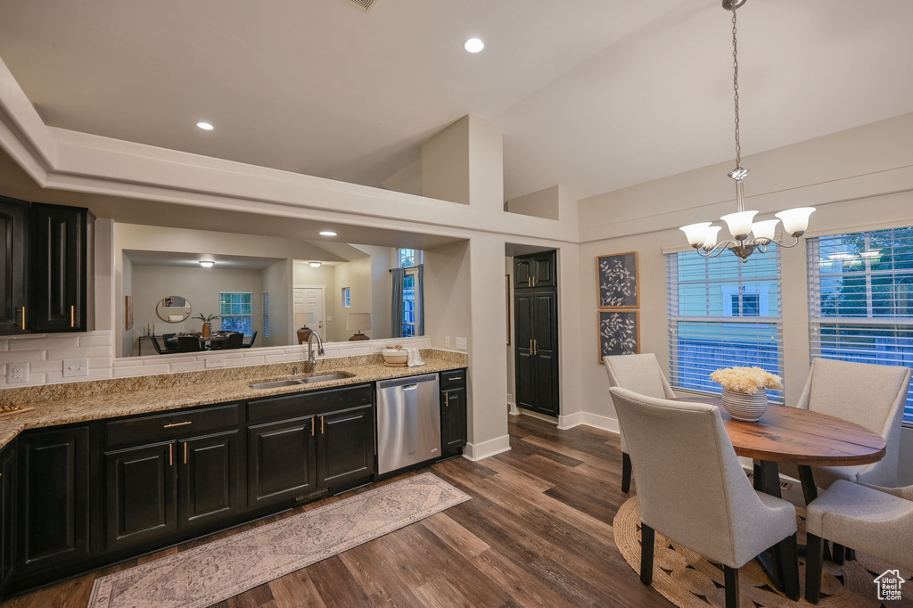 Kitchen with stainless steel dishwasher, a sink, dark cabinets, a chandelier, and dark wood-style floors
