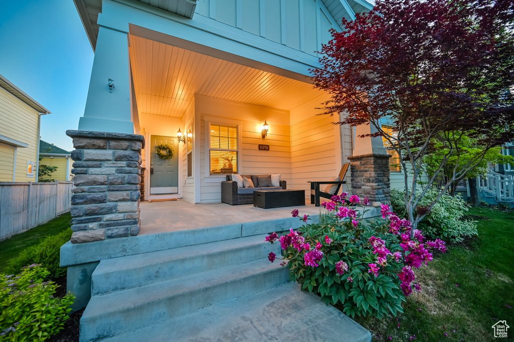 Entrance to property with board and batten siding, an outdoor living space, stone siding, and a patio area
