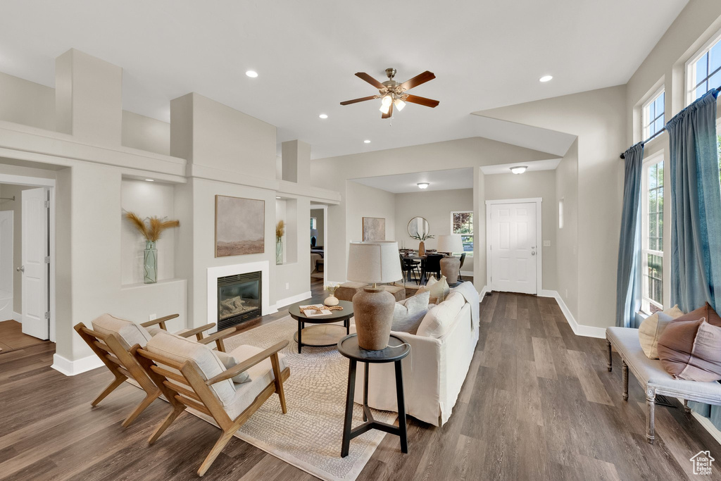 Living area featuring dark wood-style floors, baseboards, recessed lighting, a glass covered fireplace, and ceiling fan