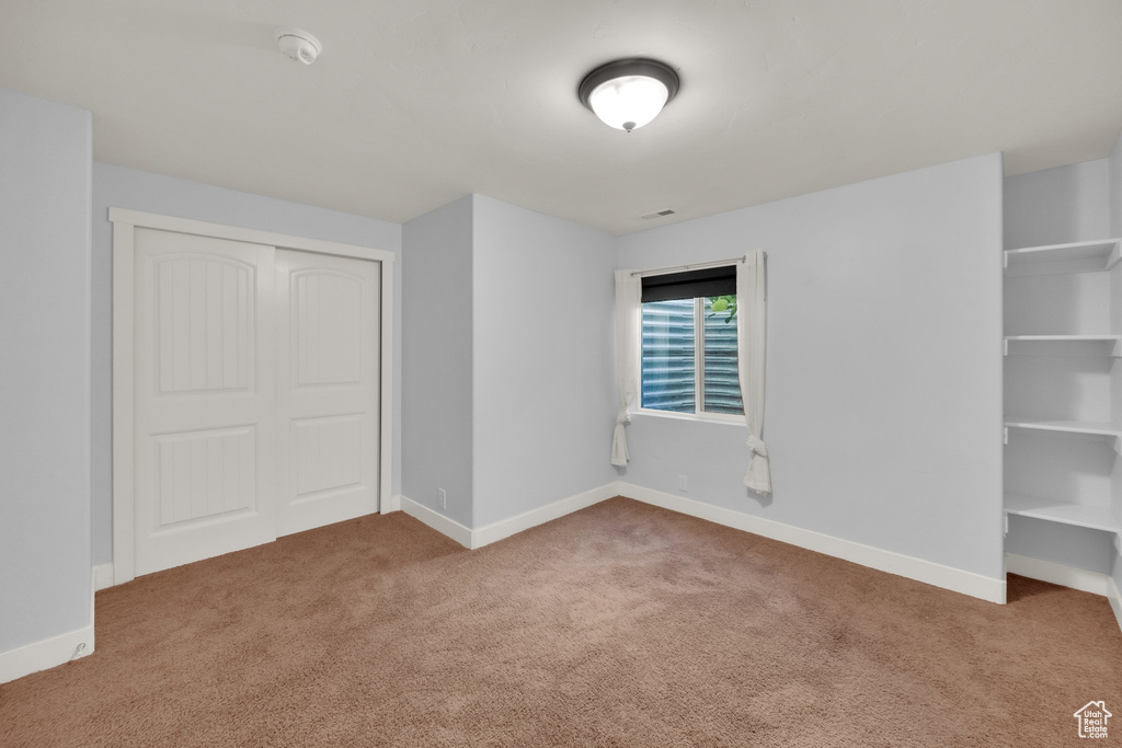 Unfurnished bedroom with carpet, a closet, and baseboards