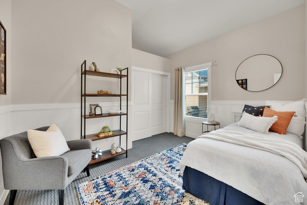 Bedroom featuring a wainscoted wall, carpet, vaulted ceiling, and a closet