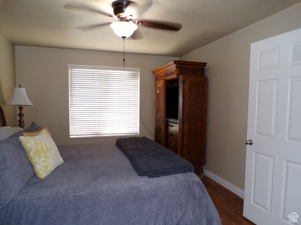 Bedroom featuring a ceiling fan, baseboards, and dark wood-style floors