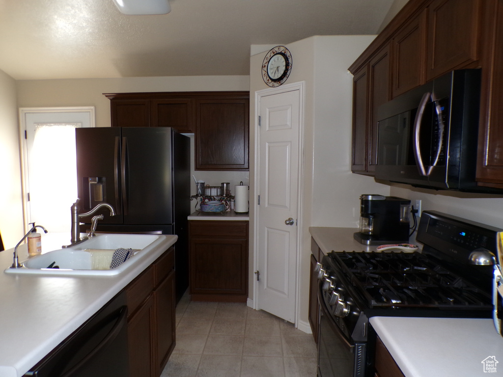 Kitchen featuring black appliances, a sink, light countertops, and light tile patterned floors