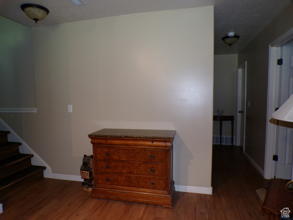 Hall featuring wood finished floors, baseboards, and stairs