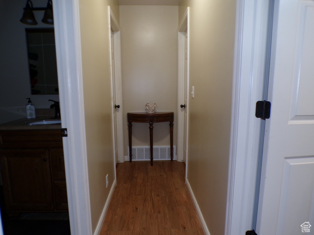 Hallway with wood finished floors, a sink, and baseboards