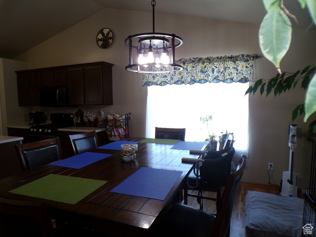 Dining space featuring a chandelier, vaulted ceiling, and wood finished floors