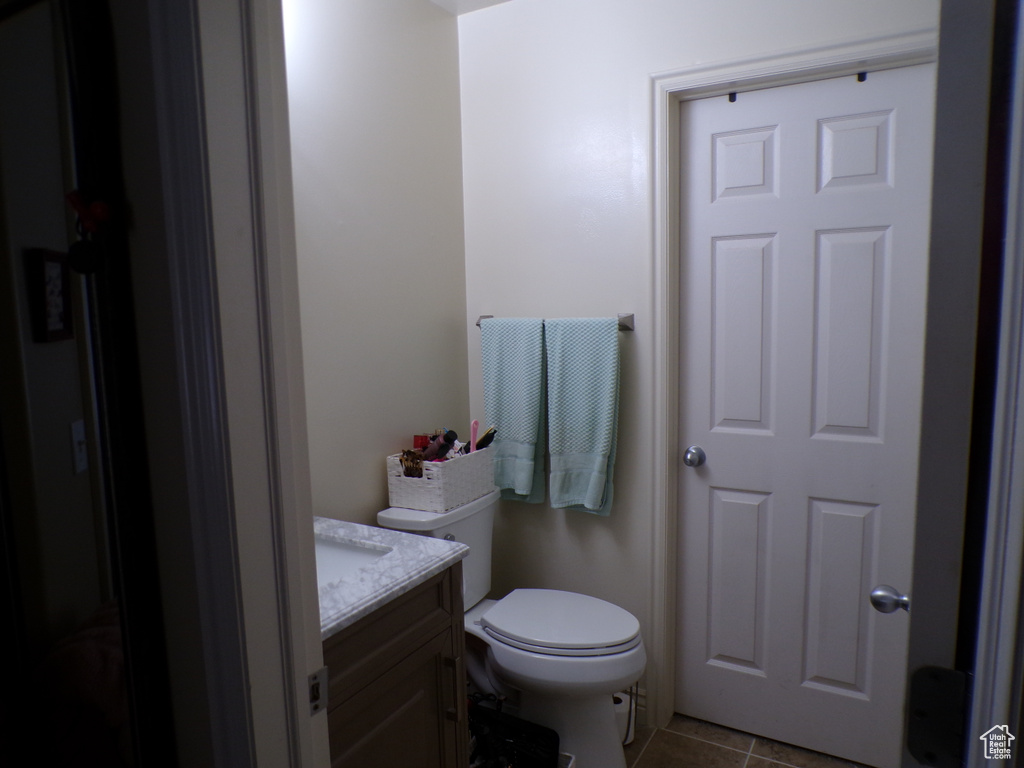 Half bathroom with vanity, tile patterned flooring, and toilet