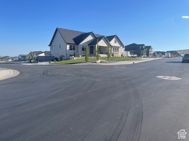 View of asphalt road with a residential view, sidewalks, and curbs