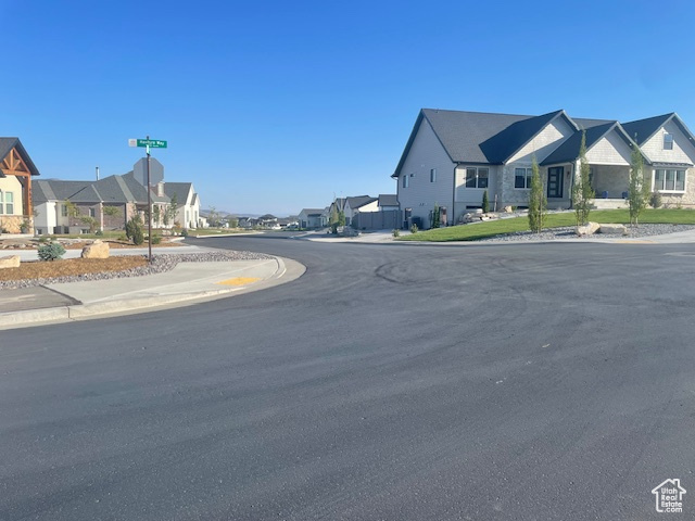 View of asphalt street featuring a residential view, sidewalks, and curbs
