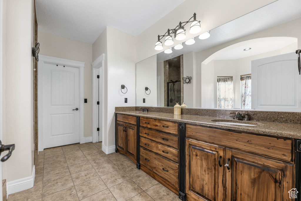 Bathroom with double vanity, tile patterned flooring, a shower with curtain, and baseboards