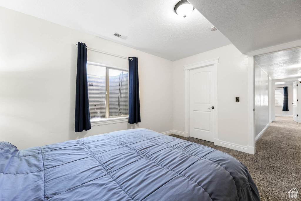 Carpeted bedroom featuring baseboards and a textured ceiling
