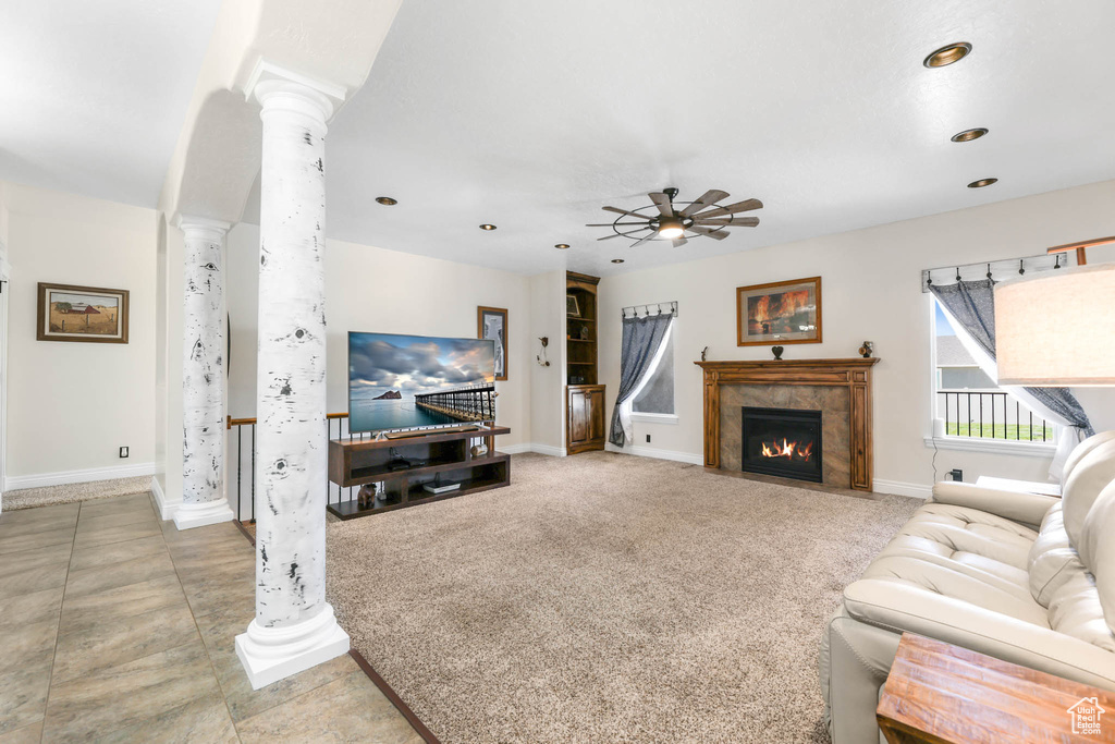 Living area featuring decorative columns, a ceiling fan, a tiled fireplace, baseboards, and recessed lighting