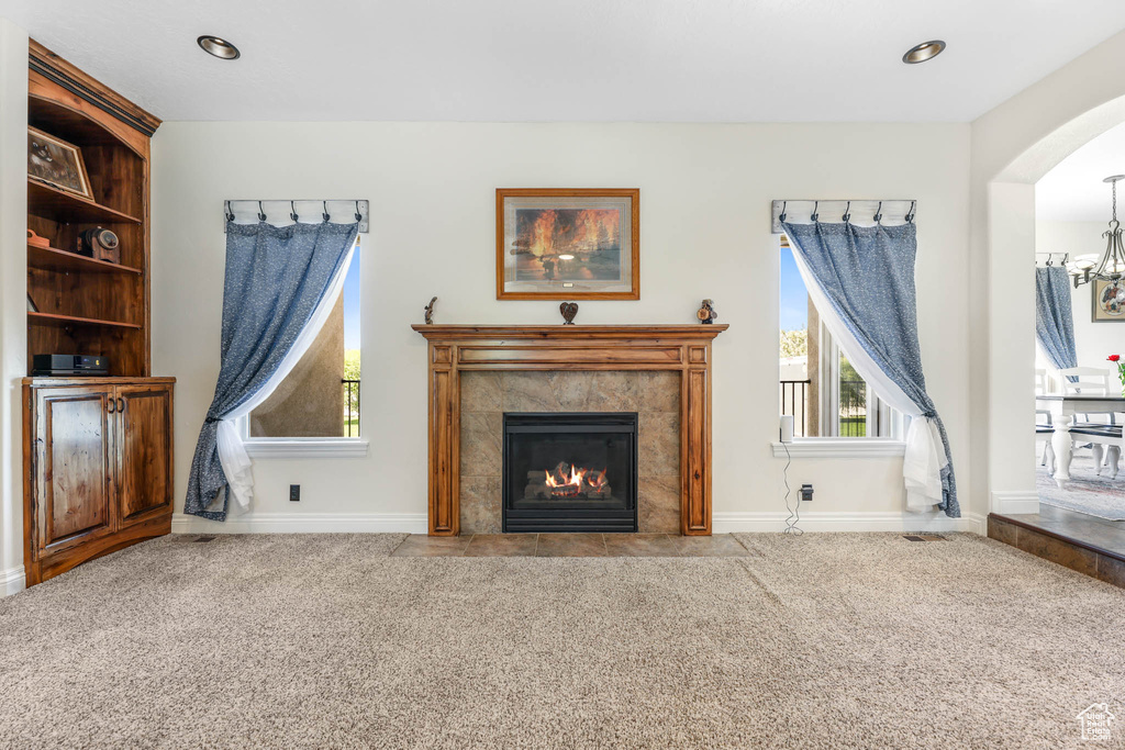 Living area with carpet, a tile fireplace, baseboards, arched walkways, and recessed lighting