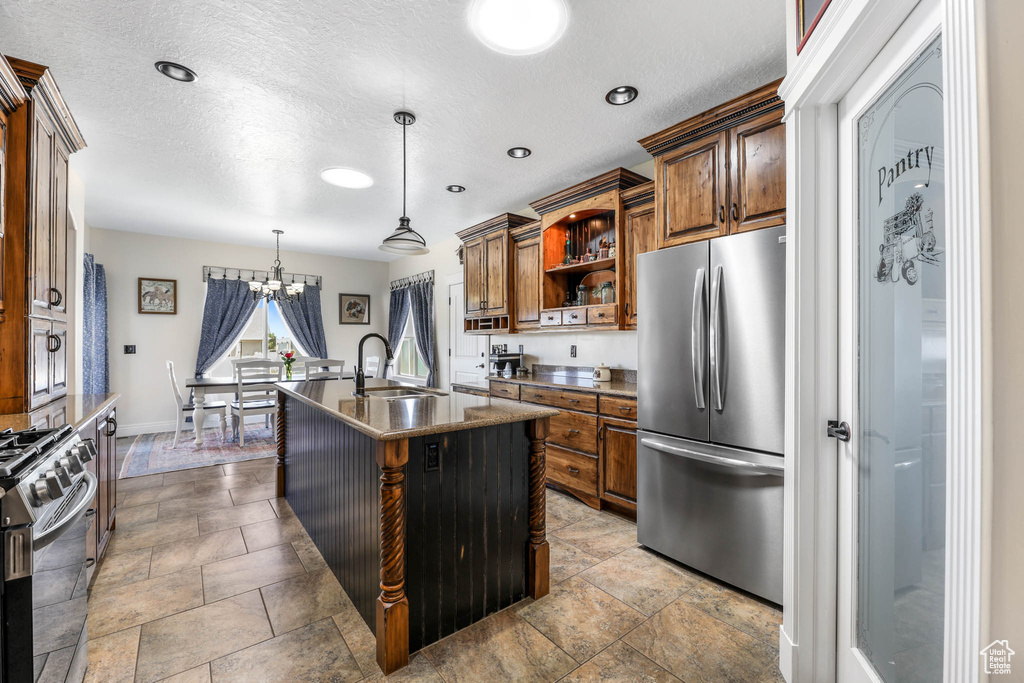 Kitchen featuring stainless steel appliances, a sink, open shelves, brown cabinets, and a textured ceiling