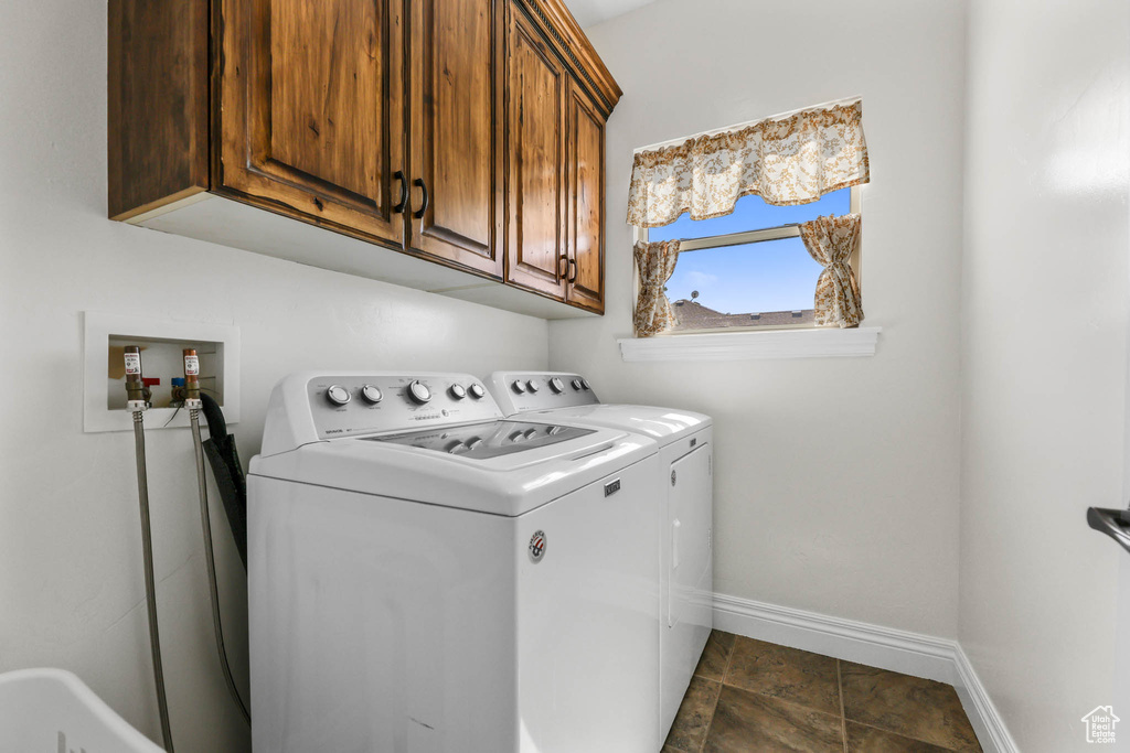 Laundry room featuring separate washer and dryer, baseboards, and cabinet space