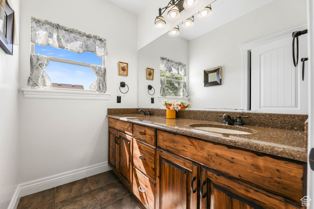 Full bathroom with double vanity and baseboards