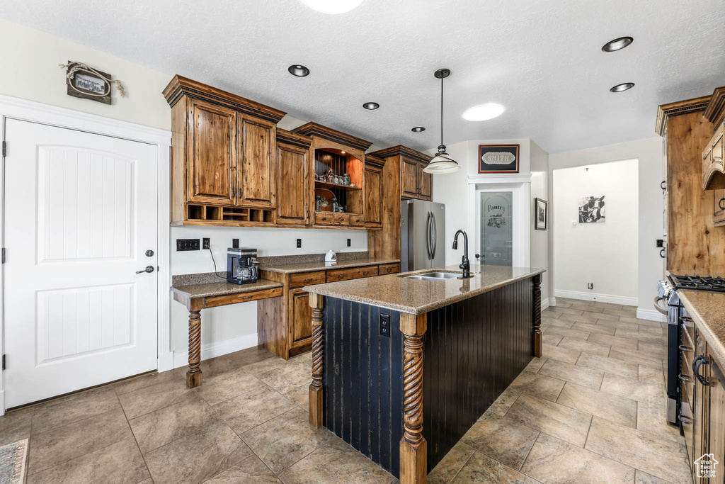 Kitchen with stainless steel appliances, open shelves, brown cabinets, baseboards, and an island with sink