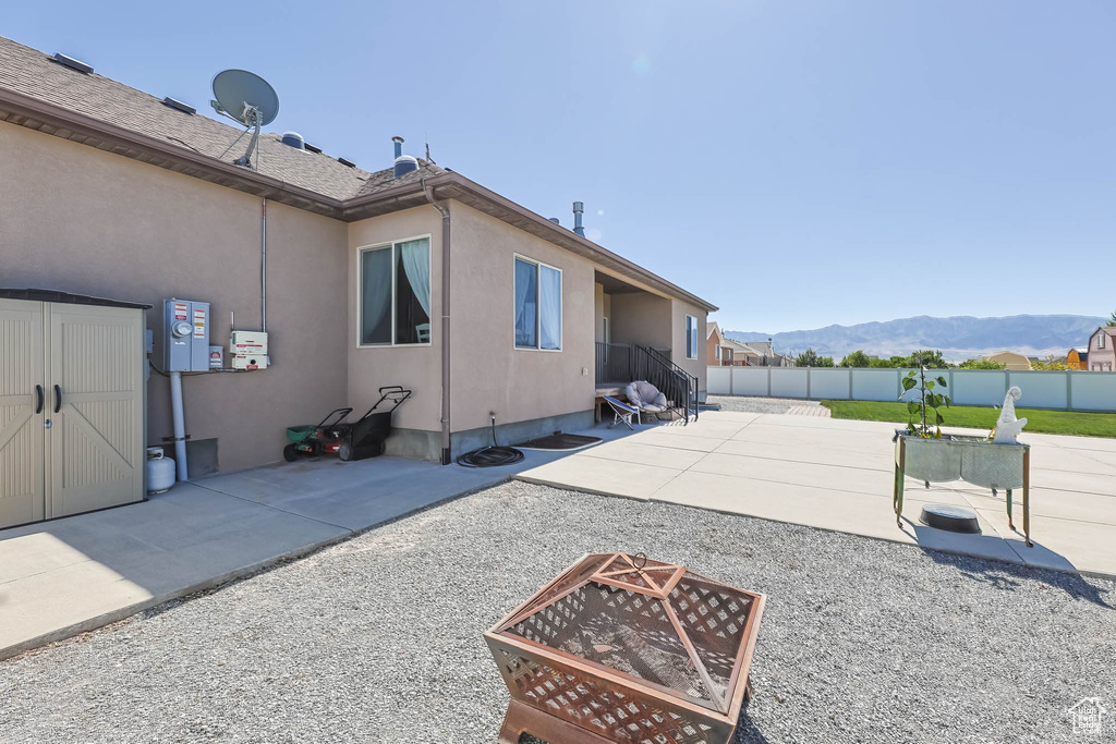 Rear view of house with an outdoor fire pit, a fenced backyard, stucco siding, a mountain view, and a patio