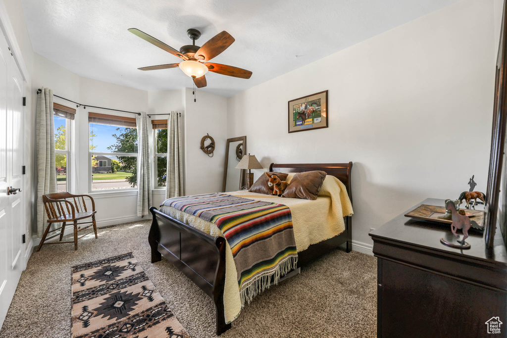 Carpeted bedroom with baseboards and a ceiling fan
