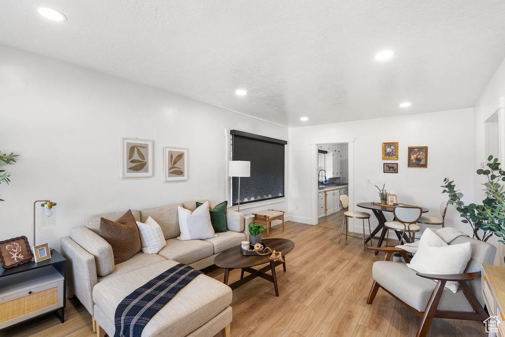 Living room with light wood-style flooring, recessed lighting, and baseboards