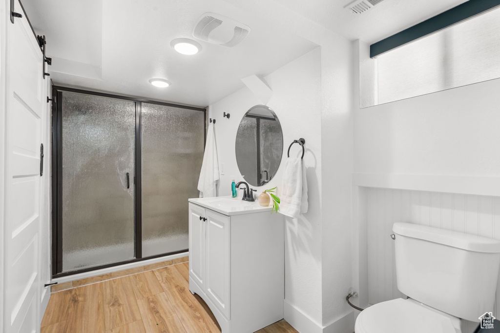Bathroom featuring vanity, wood finished floors, toilet, and a shower stall