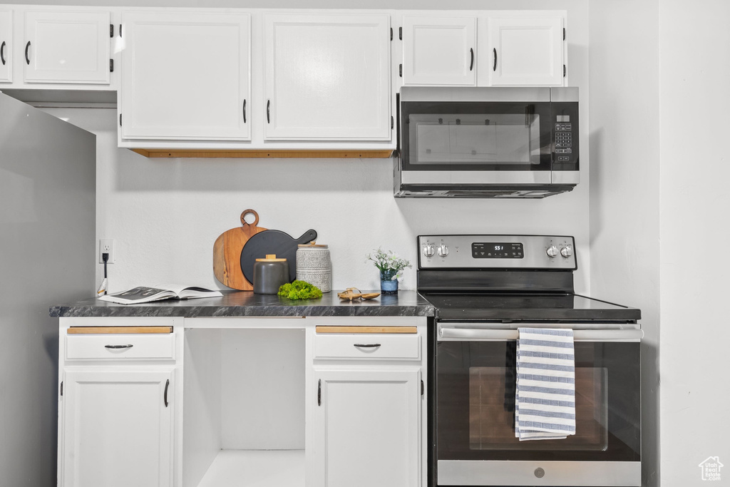 Kitchen with appliances with stainless steel finishes, white cabinetry, and dark countertops