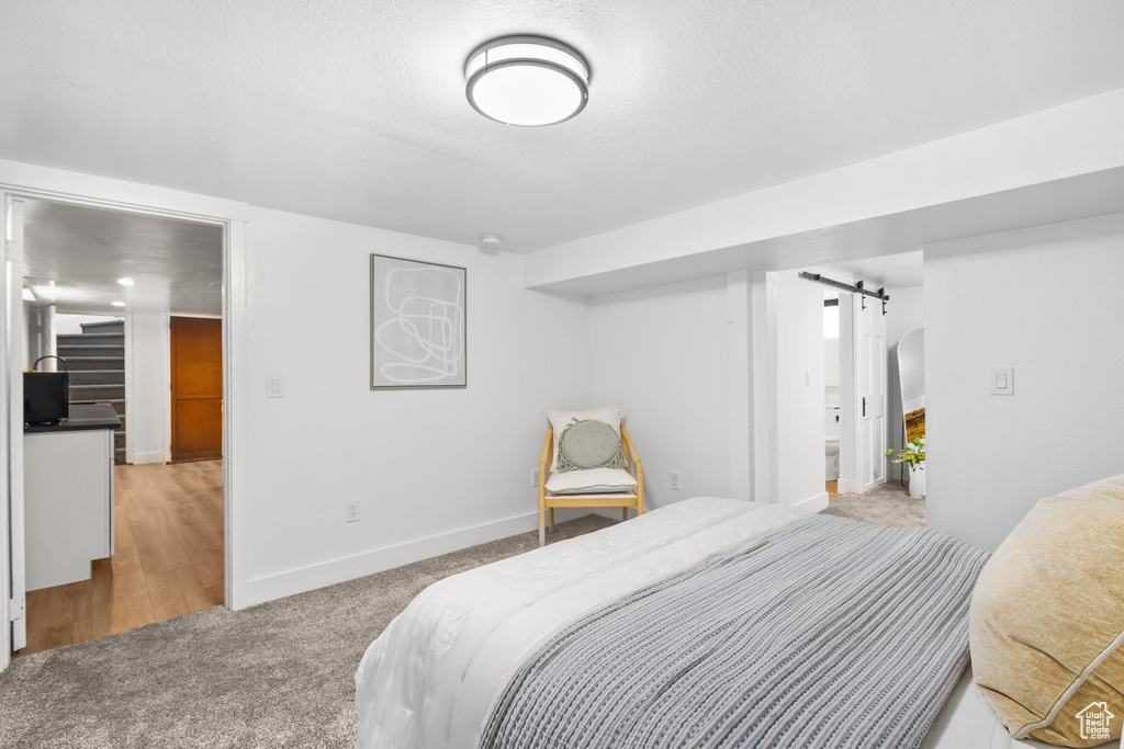 Bedroom with a barn door, carpet, and baseboards