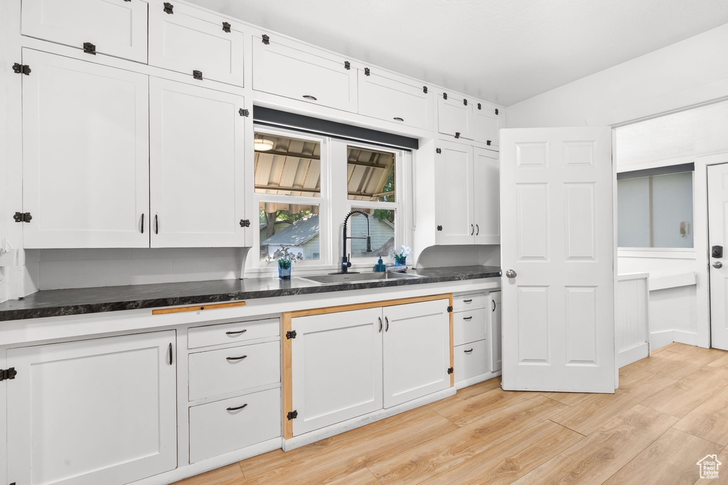 Kitchen featuring a sink, light wood-type flooring, and white cabinetry