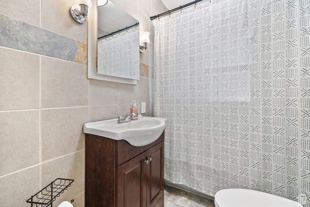 Full bath with tile walls, vanity, toilet, and a shower with curtain