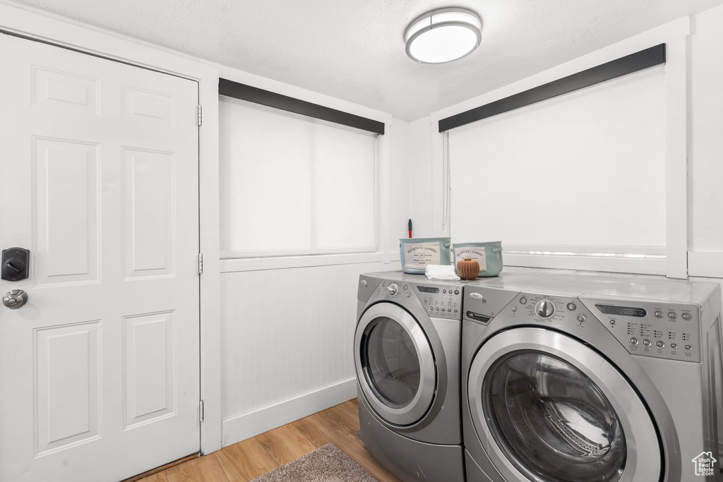 Laundry area featuring independent washer and dryer, light wood finished floors, and baseboards