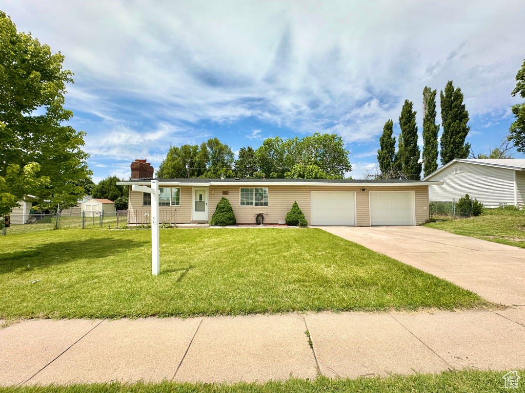 Ranch-style home with driveway, an attached garage, and a chimney
