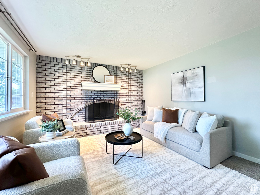 Living room with a fireplace, rail lighting, a textured ceiling, and baseboards