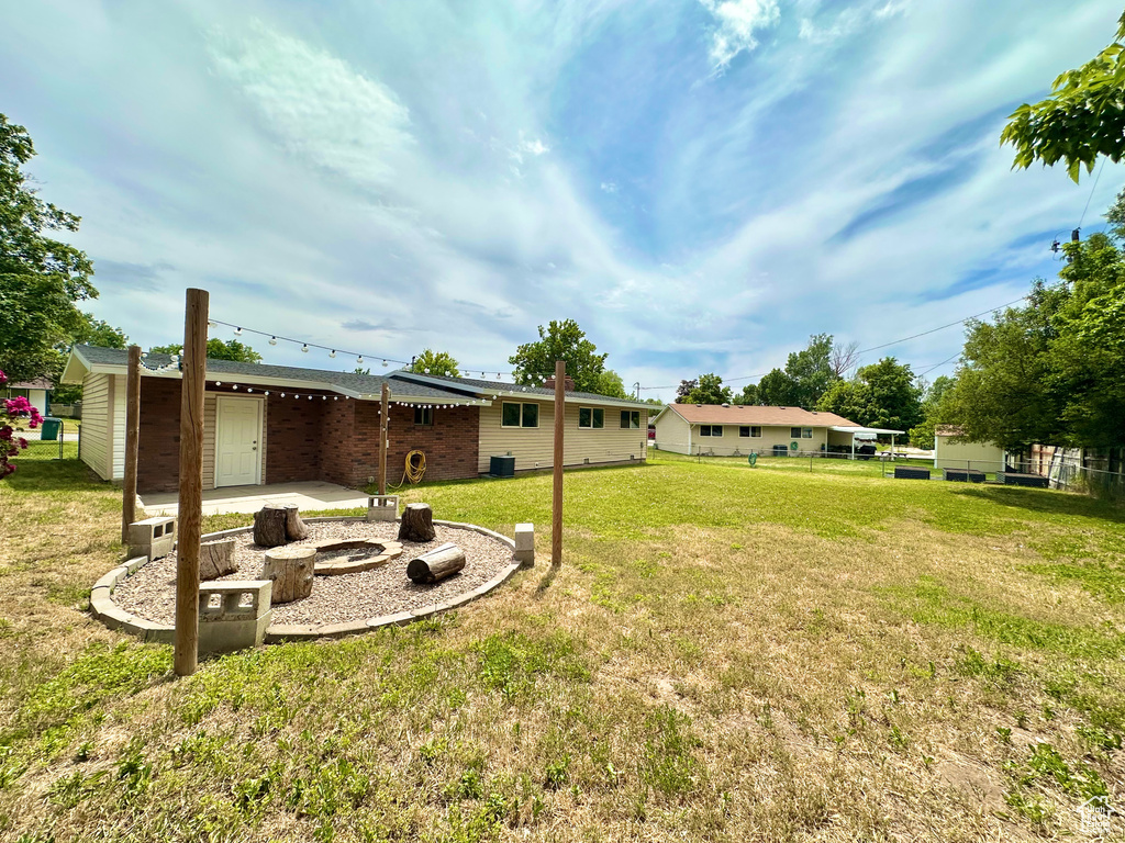 View of green lawn with an outdoor fire pit and a patio