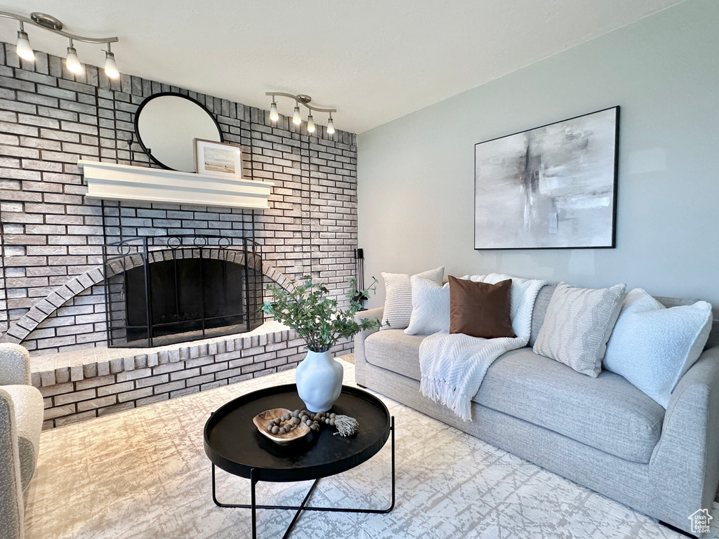 Living area with track lighting, a fireplace, and brick wall