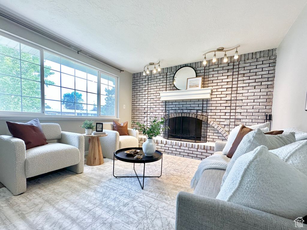 Living area with a textured ceiling, a brick fireplace, and brick wall