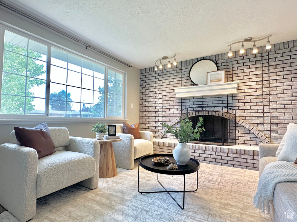 Living area with brick wall, a textured ceiling, rail lighting, and a fireplace